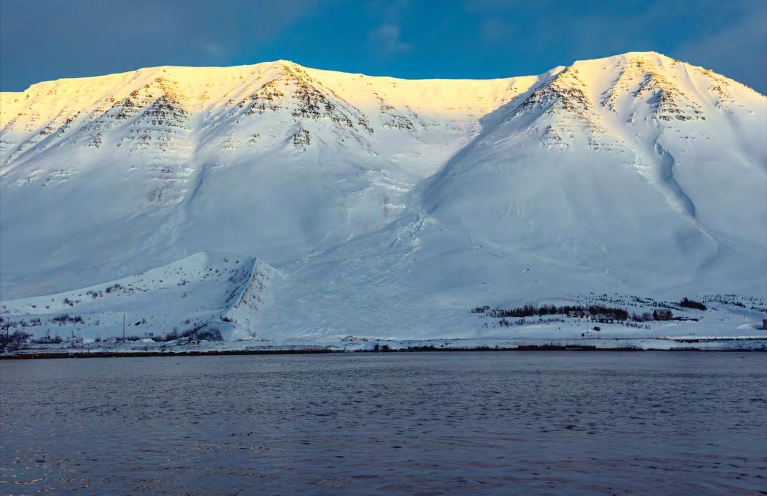 Snævi þakin fjöll með snjóflóðavarnargarði